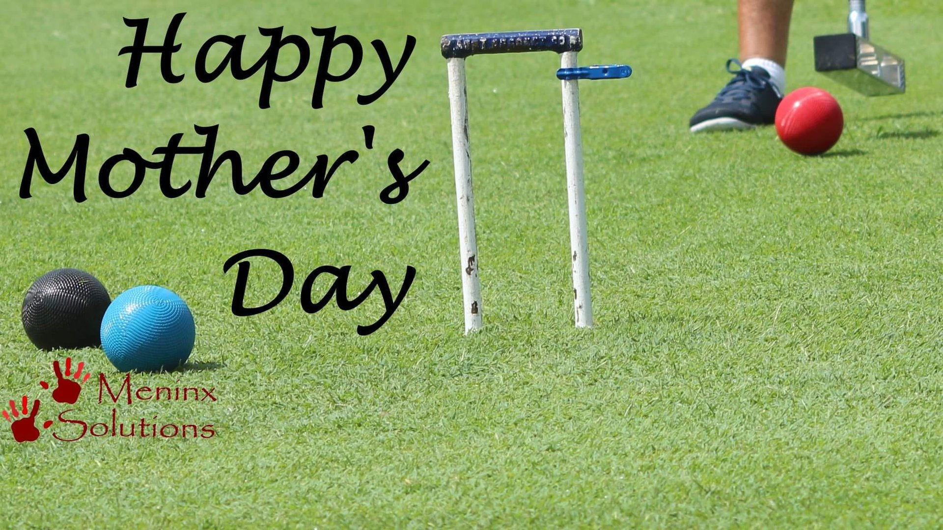Black and blue croquet balls near hoop on manicured lawn with player and mallet visible