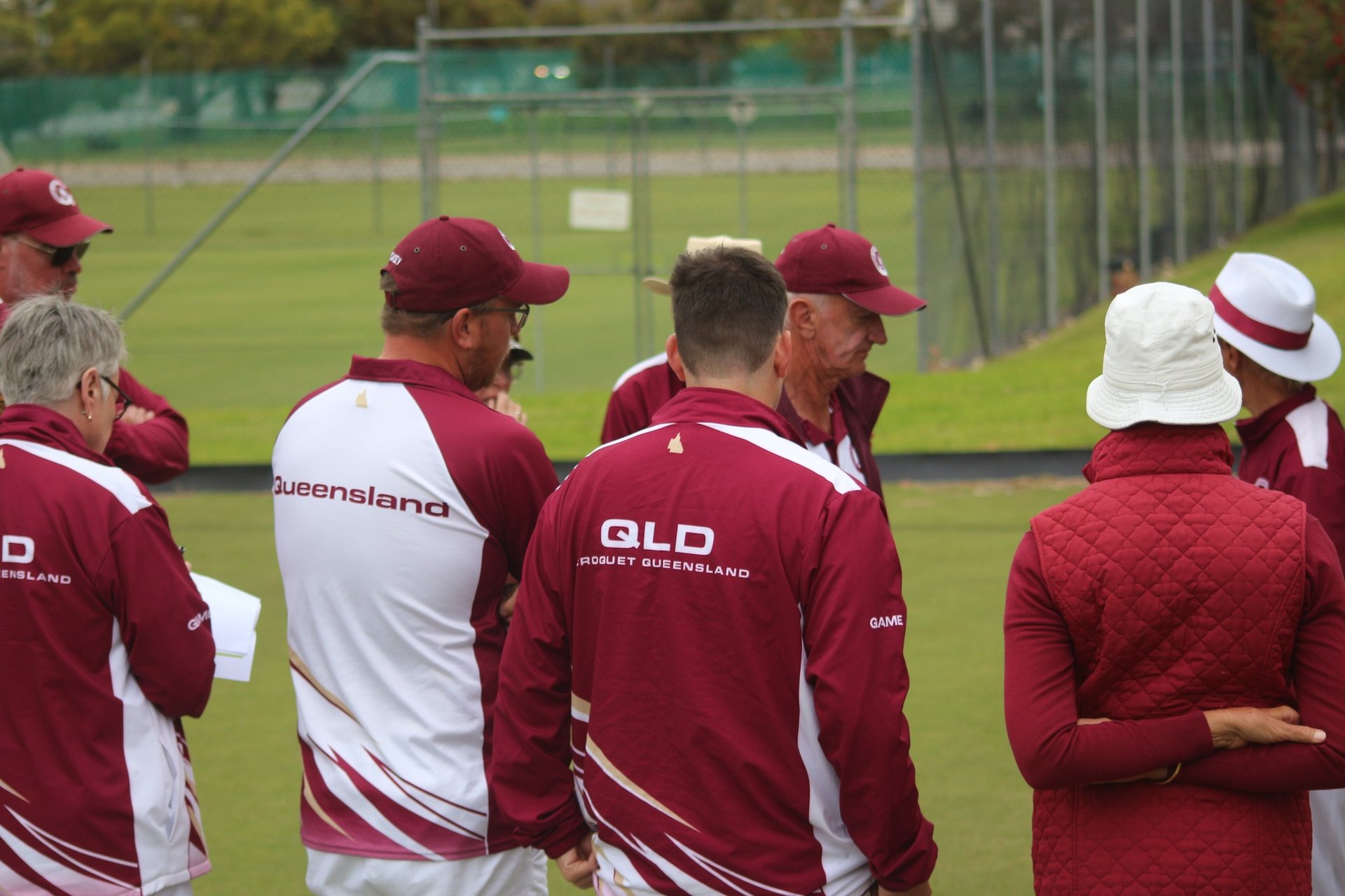Team in maroon and white uniforms gathered on croquet lawn during match or training session