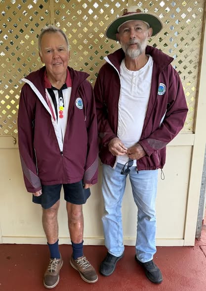 Two men in matching maroon croquet jackets stand side-by-side, one wearing a referee's ball necklace